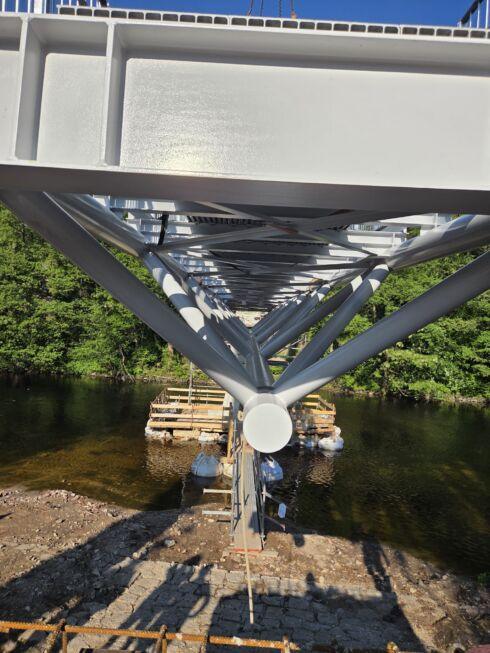 Unteransicht einer Stahlbrücke mit Fachwerkkonstruktion über einer Flussquerung