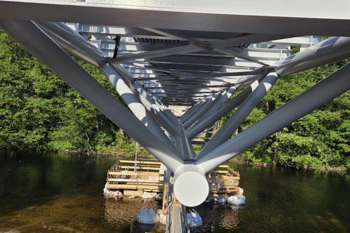Unteransicht einer Stahlbrücke mit Fachwerkkonstruktion über einer Flussquerung