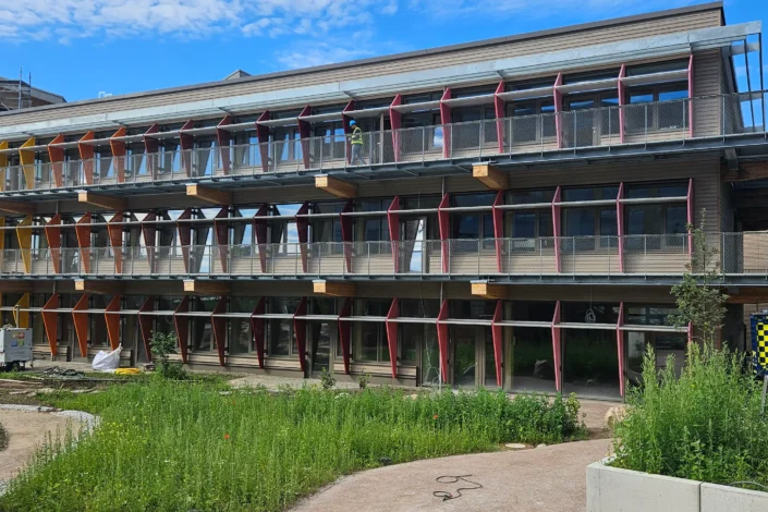 Fassadenansicht des Life Campus Hamburg mit Fluchtbalkonen, Geländern und farbigen Sonnenschutzelementen aus Stahl