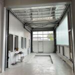 Innenansicht einer modernen Werkstatthalle in Stahlbauweise mit Arbeitsgrube und Sektionaltor