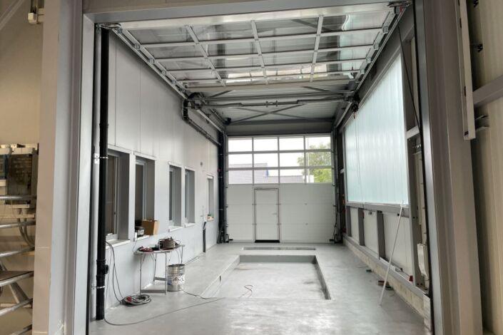 Innenansicht einer modernen Werkstatthalle in Stahlbauweise mit Arbeitsgrube und Sektionaltor