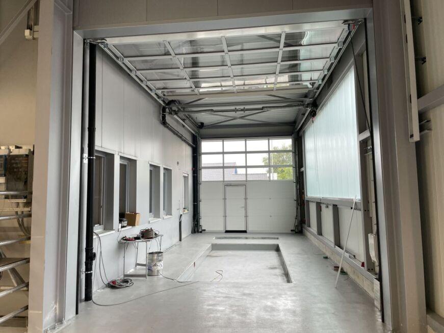 Innenansicht einer modernen Werkstatthalle in Stahlbauweise mit Arbeitsgrube und Sektionaltor